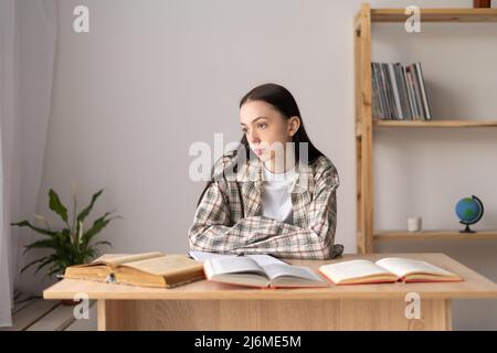 Stressed asian college student tired of hard studying with books while preparing for exams, overworked high school student exhausted from hard study Stock Photo
