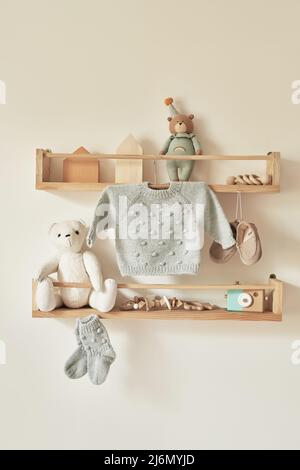 Children's knitted clothes on hanger. Jacket, jumper, hat, shoes. toys. Children's room, nursery. Stock Photo