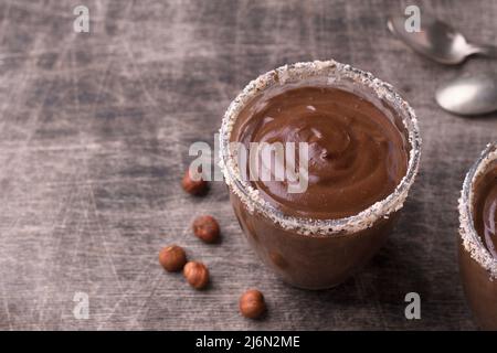 Chocolate mousse with cream and hazelnuts in glasses on old dark wooden table Stock Photo
