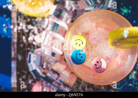 Conceptual image about spare funny time at a disco party drinking fresh coctails and in the other hand about alcoholic and drug abuse during the celeb Stock Photo