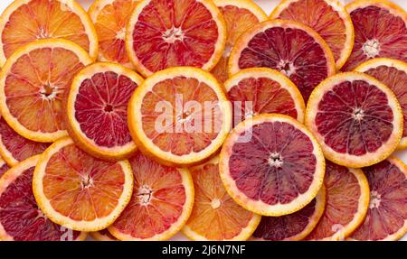 Sliced blood oranges circles on white plate, top view, close-up, horizontal Stock Photo