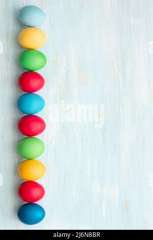Colorful easter eggs on a blue background, top view, space, vertical Stock Photo