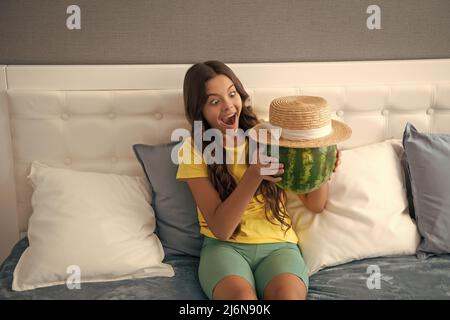 shocked kid holding fresh ripe water melon fruit in summer straw hat, food Stock Photo