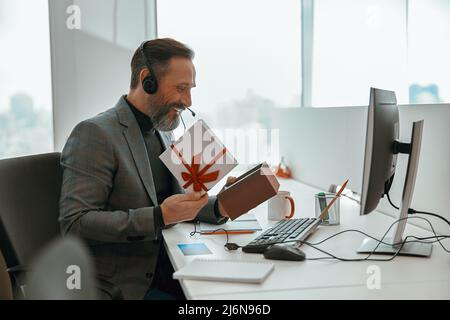 Smiling manager holding box and opening it Stock Photo