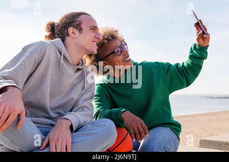 couple of young friends smiling while taking a selfie photo with the mobile phone, concept of friendship and technology Stock Photo