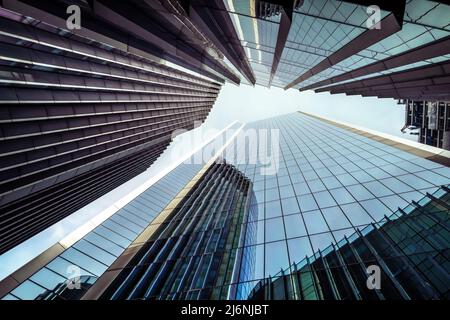 Looking up at modern architecture to the sky. Windows and reflections on a clear day in London, UK. Stock Photo