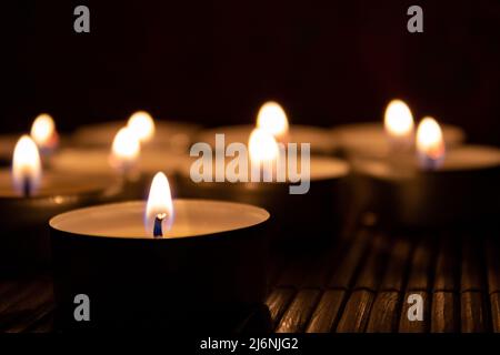 Close-Up of Lit Tealight Candles Creating a Warm and Relaxing Atmosphere in the Dark Stock Photo