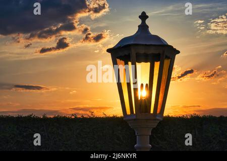 A glass lantern through which the setting sun shines from behind. Stock Photo