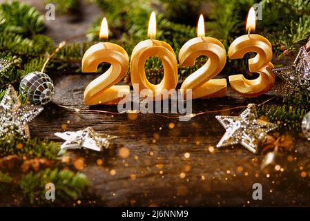 Holiday background Happy New Year 2023. Numbers of year 2023 made by gold burning candles on bokeh festive sparkling background. celebrating New Year Stock Photo