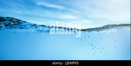 fresh clear water wave with bubbles on blue sky background. banner Stock Photo