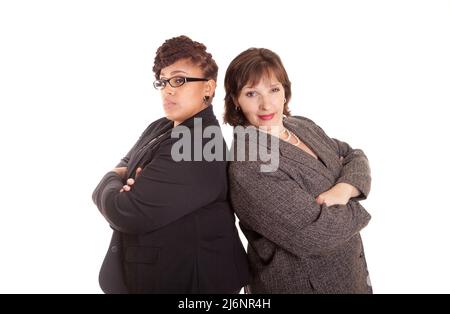 Two confident plus size mixed race business women on a white background standing back to back in a confident sly pose Stock Photo