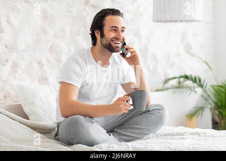 Relaxed man having phone call while drinking coffee Stock Photo