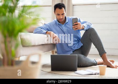 Portrait of focused man using smartphone and pc at home Stock Photo