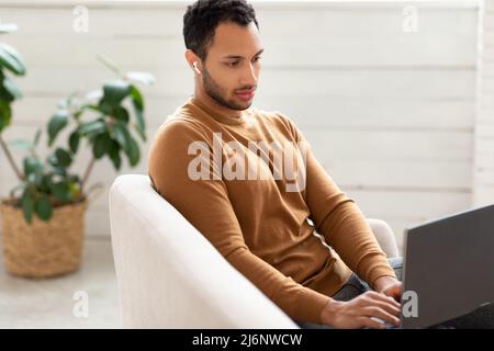 Arab man using laptop sitting on couch at home Stock Photo