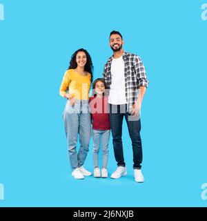 Modern Arabic Family Standing Embracing On Blue Background Stock Photo