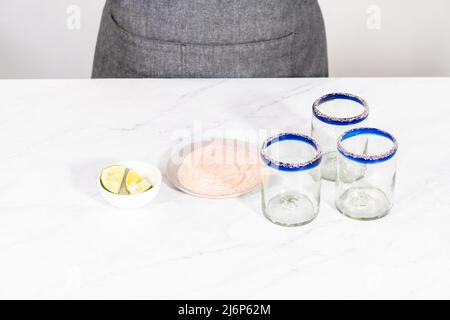 Garnishing edged of the glass with salt for frozen watermelon margarita. Stock Photo