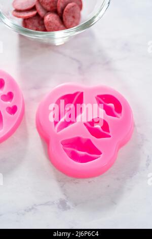 Filling silicone mold with melted chocolate to make chocolate lips and heart-shaped chocolates for Valentine's Day. Stock Photo