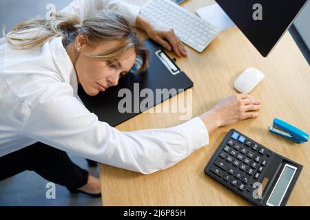 Exhausted depressed business woman leaned her head on her work desk Stock Photo