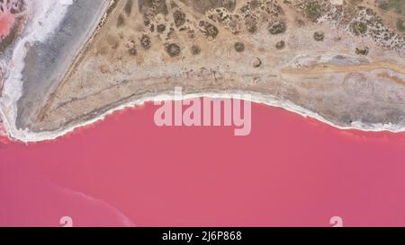 Flying over a pink salt lake. Salt production facilities saline evaporation pond fields in the salty lake. Dunaliella salina impart a red, pink water Stock Photo