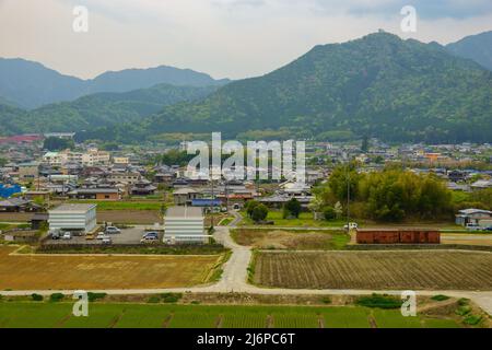 Empty T-intersection at road next to small country village with mountains in background Stock Photo