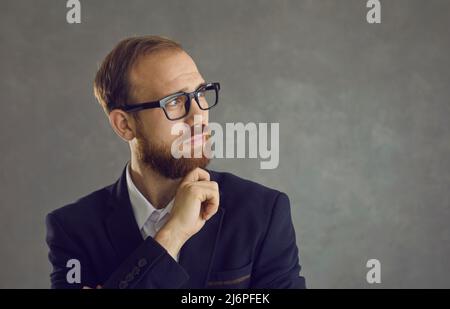 Portrait of a pensive man with glasses looking at the free space for text touching his chin. Stock Photo