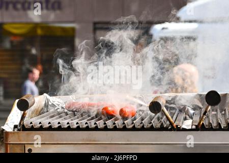 Strasbourg, France - April 2022: Smoke from frankfurter sausages cooking on an outdoor grill on a market stall in Strasbourg city centre Stock Photo