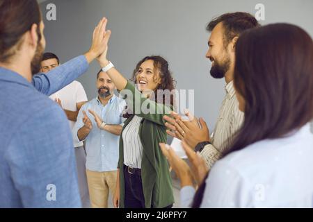 Group of excited people giving each other ahigh five after productive corporate meeting in office. Stock Photo