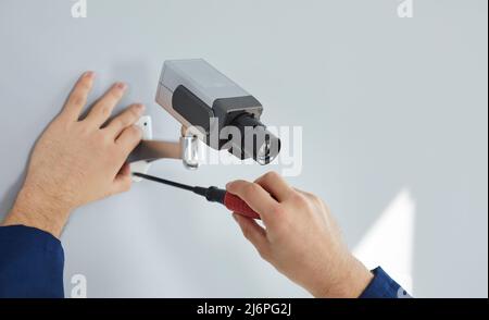 Process of installing surveillance camera on wall for security inside new home or office. Stock Photo