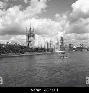 1950s, London, historical view from this era from the South Bank across the river Thames to the Palace of Westminster, the location of the two Houses of Parliament of the UK Government. The Palace has three towers, the tallest, the Victoria Tower, then the Central Tower and in the far distance, the Elizabeth Tower, previously the Clock Tower but commonly known as Big Ben after its main bell. Stock Photo