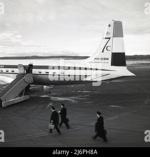 1950s, historical, pilots on the runway walking to board a Douglas DC-7C. KLM aircraft at Anchorage airport, Alaska, USA. Introduced in 1956, the DC-7C (Seven Seas) was an extended range variant of the original DC-7 aircraft, with improved engines and added fuel capacity. These alterations meant it had non-stop transatlantic capacity and were added to attract  European aircarriers. The numbers 7c can see on the tailplane. Stock Photo