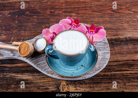 Close up white cup of salep milky hot drink on wooden background. Cup of salep milky traditional hot drink of Turkey with cinnamon served in a porcela Stock Photo