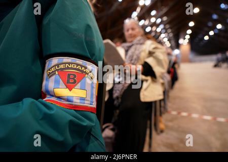 03 May 2022, Hamburg: Members of the Belgian Amicale, an association of survivors and relatives of former concentration camp prisoners, wear an armband in the national flags of Belgium, during the commemoration ceremony at the Neuengamme Concentration Camp Memorial to mark the 77th anniversary of the end of the war and the liberation of the prisoners. Survivors as well as member associations of the Amicale Internationale KZ Neuengamme and other relatives of former Neuengamme Concentration Camp prisoners from Belgium, Denmark, Germany, France, Croatia, the Netherlands, Poland and Spain and Ukra
