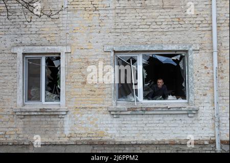 Irpin city, Ukraine, April 11, 2022. War in Ukraine. A man stands at a broken window after an attack by Russian soldiers Stock Photo