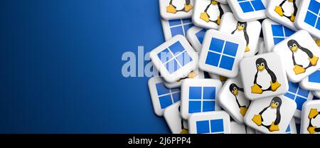 Logos of the competing PC operating systems Linux and Windows on a heap on a table. Copy space. Web banner format. Stock Photo