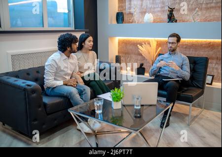 Young man and his female companion sitting in the psychologist office Stock Photo