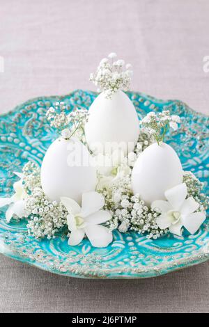 Easter floral decoration with goose egg, orchid flowers and gypsophila paniculata twigs. Festive decor Stock Photo