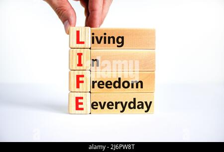 LIFE living in freedom everyday symbol. Concept words LIFE living in freedom everyday on blocks on white background. Businessman hand. Business LIFE l Stock Photo