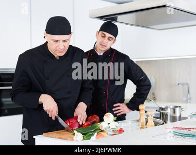 Professional men chefs in black uniform working together Stock Photo