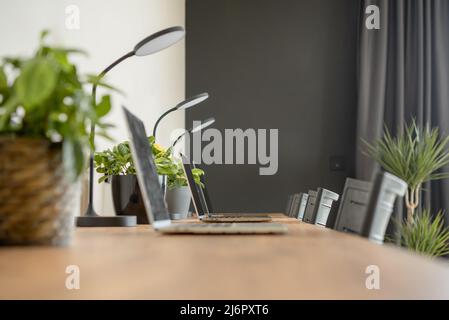 Wooden desktop with laptops in a modern interior of a cozy coworking space. Selective focus. Stock Photo