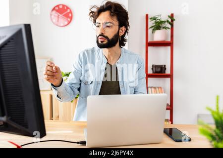 Young hipster freelancer man working concentrated on laptop computer from home Stock Photo