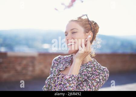 Happy young woman laughing on joke, calling by hands free device outdoors Stock Photo
