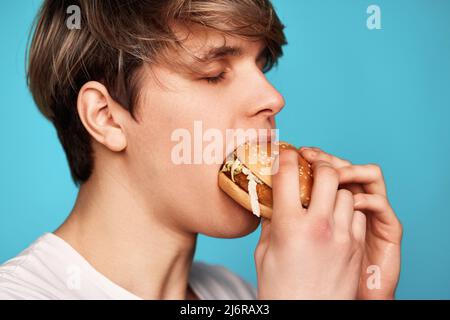 Very hungry young man holding tasty hamburger Stock Photo