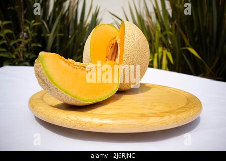 Delicious sliced fruit melon, honeydew melon or cantaloupe on wooden board with nature background. Favorite fruit in summer on white background. Stock Photo