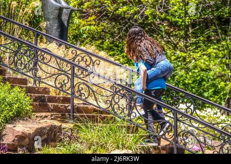 High school kids goofing around in park - boy climbing stairs with long haired girl riding piggy back - selective focus and motion blur Stock Photo
