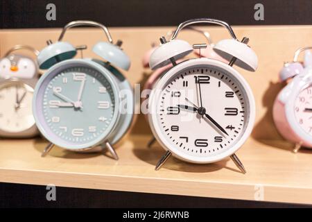 Round alarm clock on the store shelf close-up. Sale of various watches and alarm clocks of different colors. Retro alarm clock on the table, vintage t Stock Photo