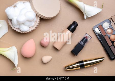 Composition with decorative cosmetics, makeup sponges, cotton balls and calla lilies on color wooden background Stock Photo