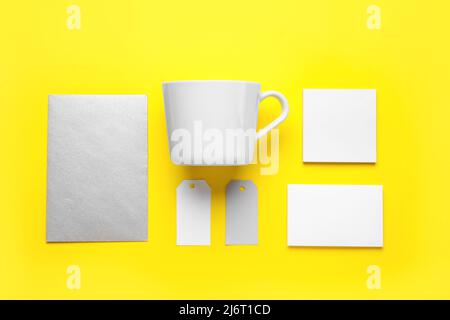 Blank cup, cards and tags on yellow background Stock Photo