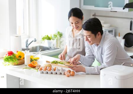 In the family kitchen, a young couple enjoy cooking together. They use tablets to check cooking tutorials - stock photo Stock Photo