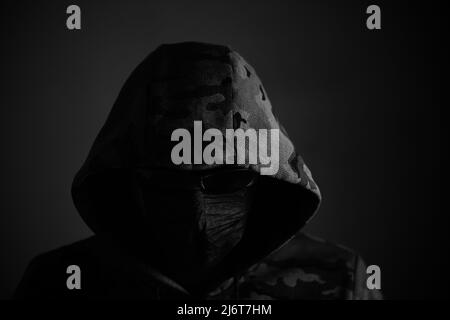 Stylish man in dark hoodie with black glasses and mask dark background, hacker, attacker and bandit Stock Photo