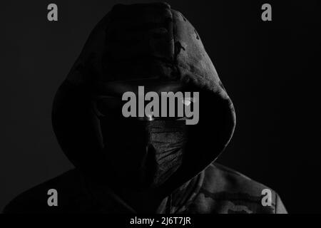 Stylish man in dark hoodie with black glasses and mask dark background, hacker, attacker and bandit Stock Photo